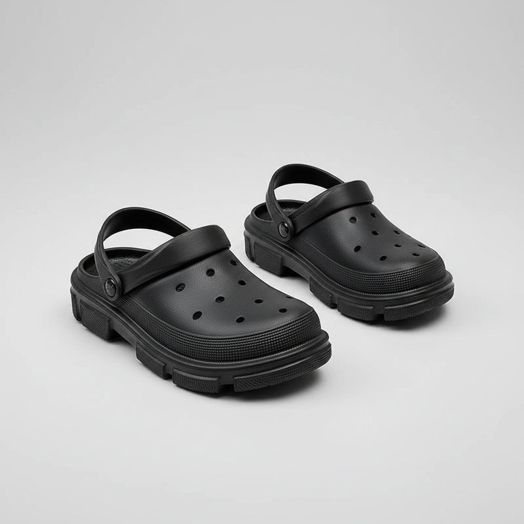 Black slip-on clogs with ventilation holes and thick sole on wooden table