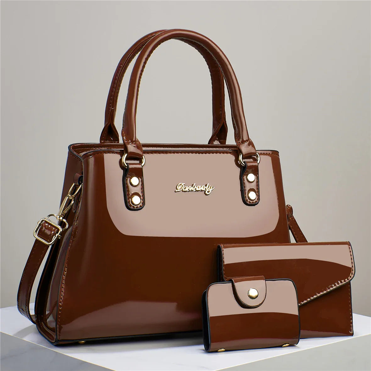 Dark brown patent leather handbag set for women with matching wallet and clutch on display.