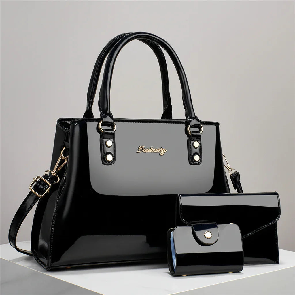 Glossy black leather handbag set with purse and wallet on a white surface