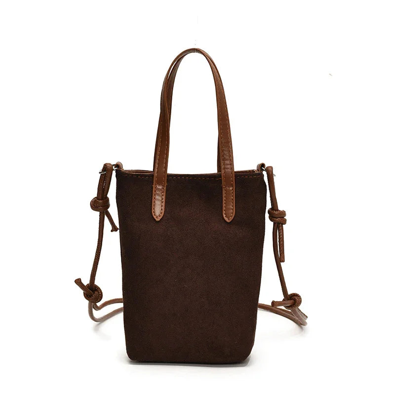 Brown suede mini tote bag with leather handles and adjustable crossbody strap on white background.