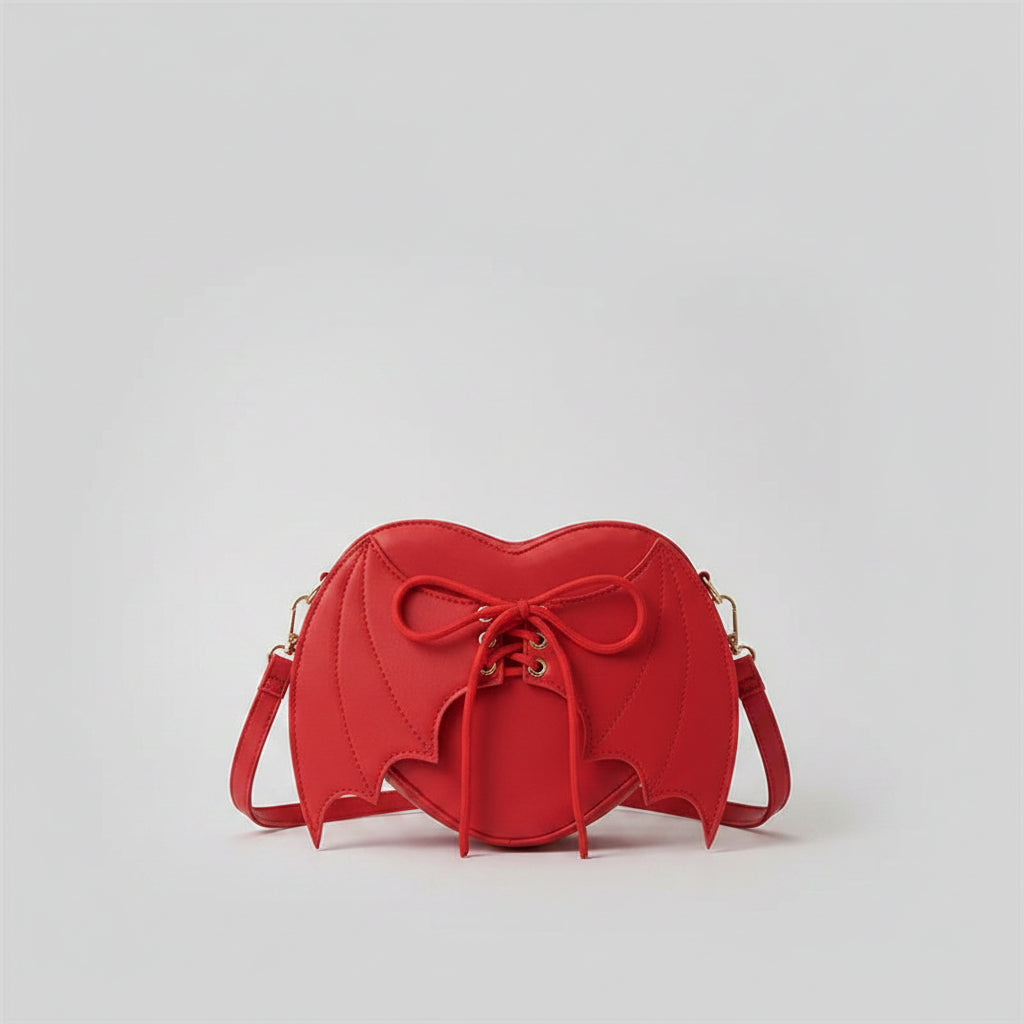 Red bat wing heart-shaped crossbody purse with laces on denim jacket background