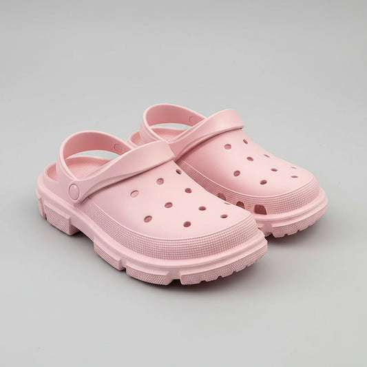 Light pink slip-on foam clogs with ventilation holes, displayed on a wooden surface