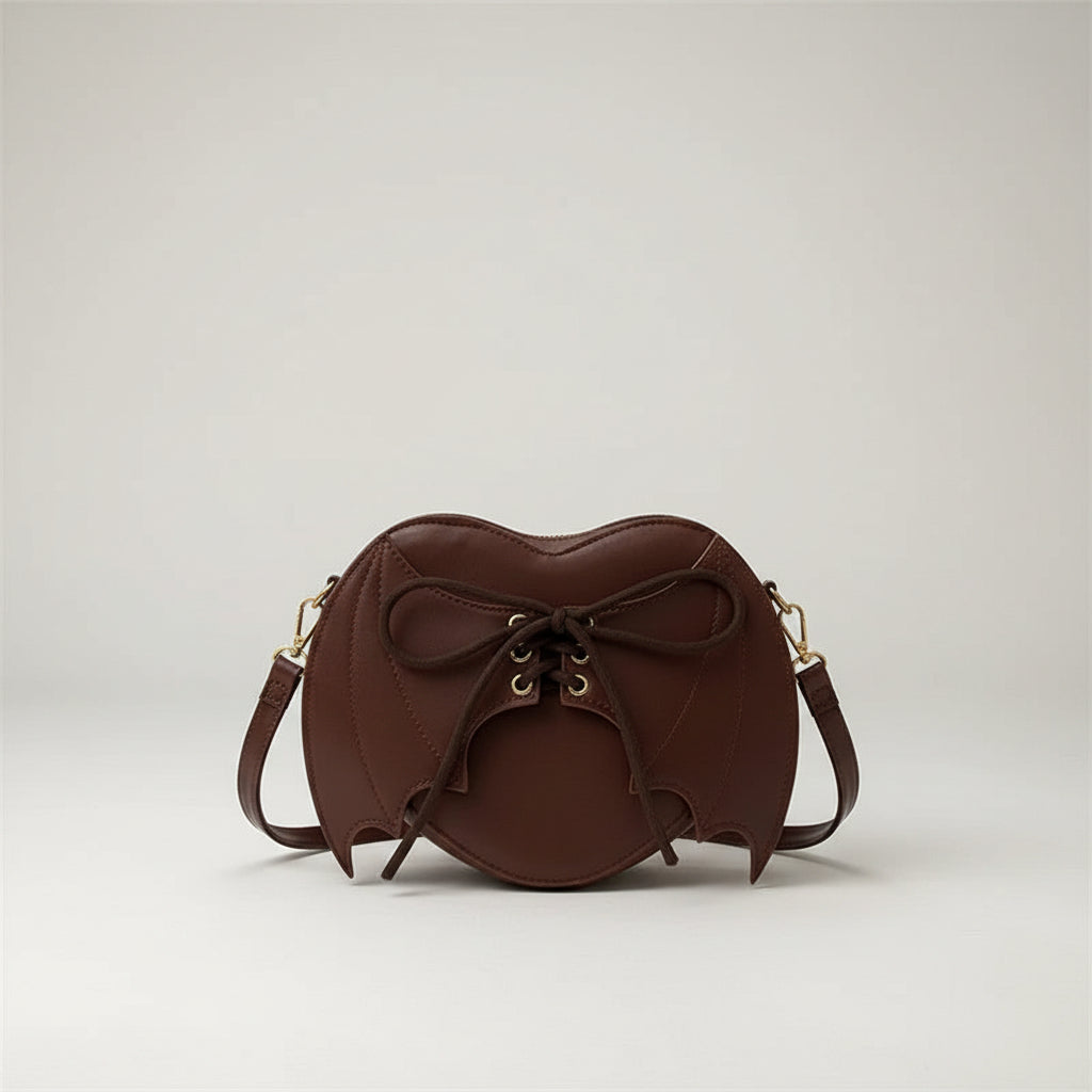 Brown bat-shaped crossbody bag with lace-up detail on denim jacket background